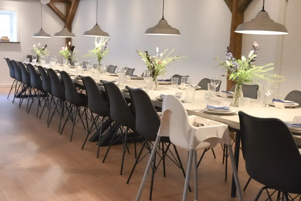 Langt opdækket spisebord med stole, blomster og service i Horsemosegaards spisesal